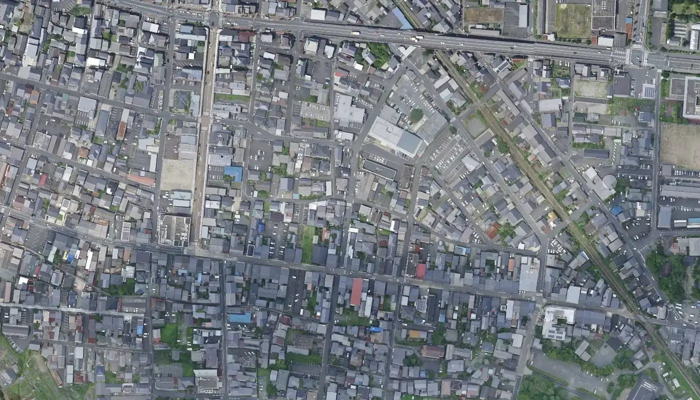 綾部市中心部の市街地を真上から見た空中写真。細い道に沿って、灰色の屋根の家がすき間なく並ぶ