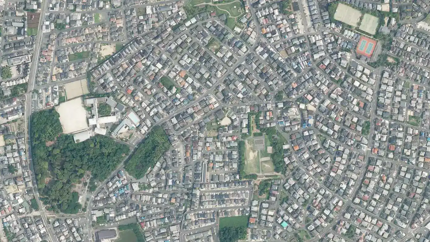 城陽市中心部の空中写真。放射状の道路に沿って戸建ての屋根が密集する住宅地。左下に緑地、右上にテニスコート