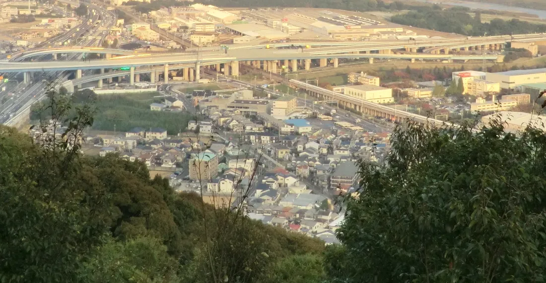 天王山から見下ろした大山崎町の町並み。一戸建ての屋根が集まる住宅地の奥に、高速道路のジャンクション